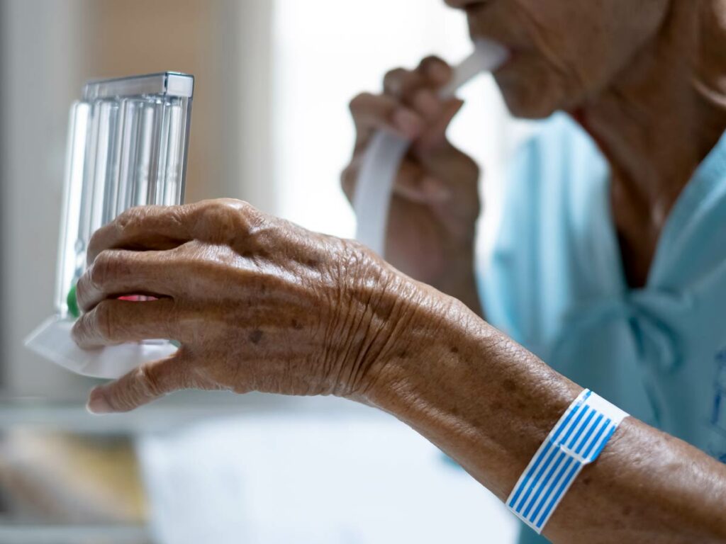 Pulmonary Rehabilitation in Hospice: A patient in a heartfelt moment using a tri-ball Incentive Spirometry, promoting respiratory well-being.