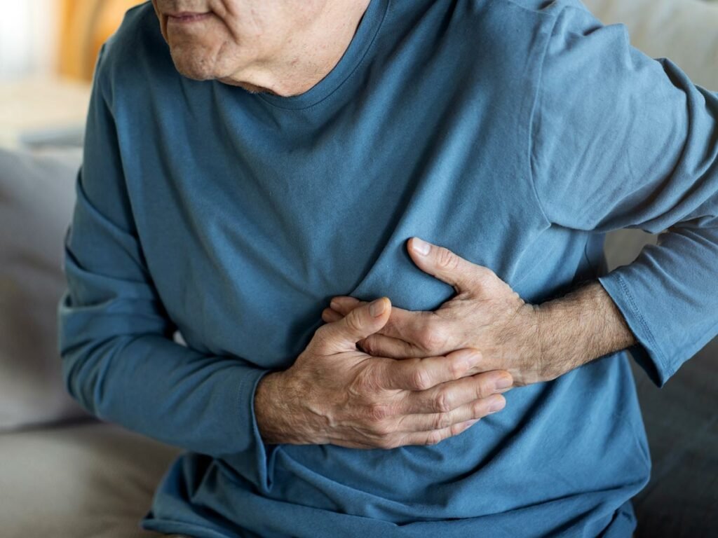 Elderly man in distress, clutching his chest due to heart disease. Urgent medical attention is crucial.