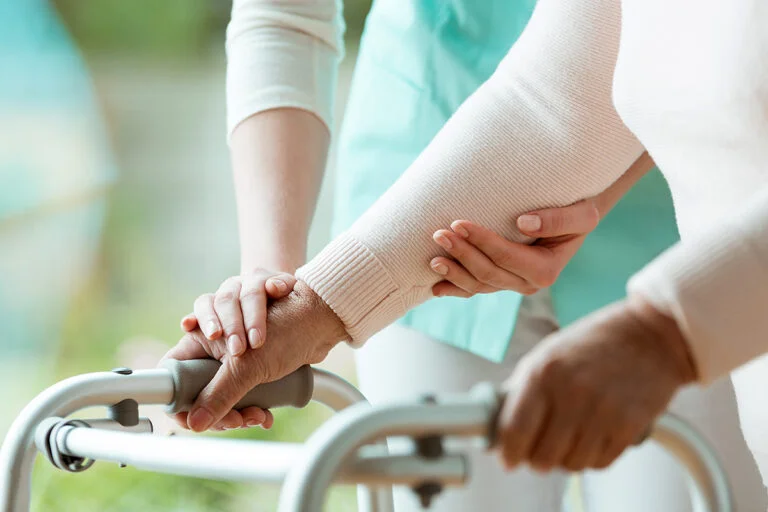 Close-up photo of patient's hands placed on metal walker