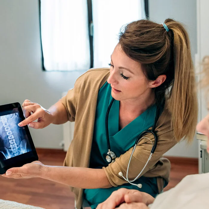 Female doctor showing to female senior patient an x-ray on the tablet